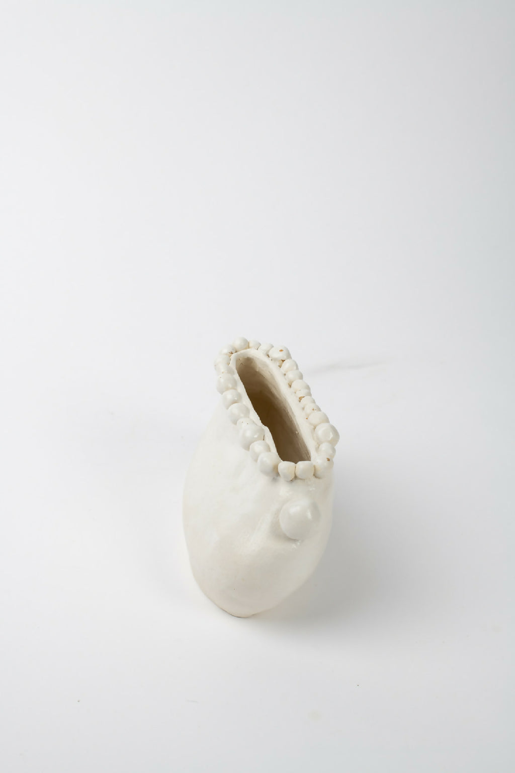 Vase en céramique blanche, vue de côté, ouverture étroite entourée de perles