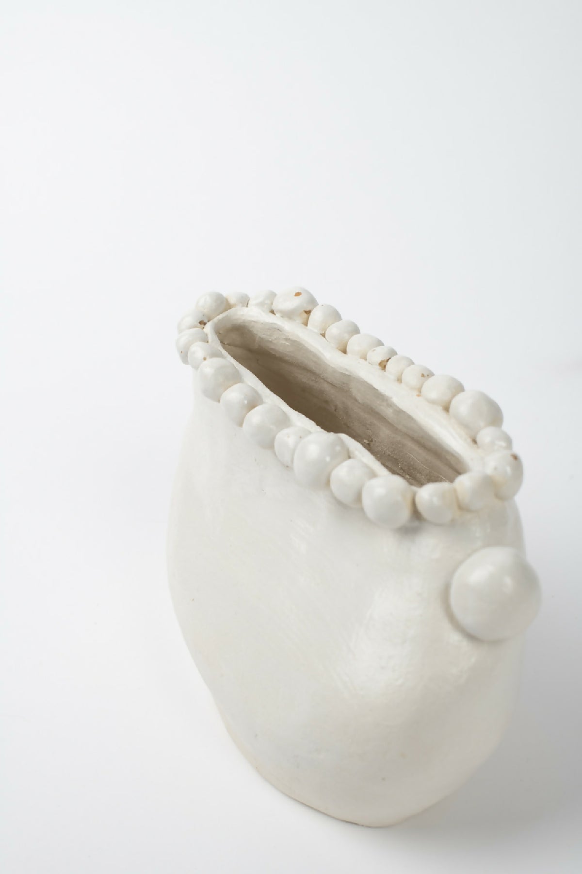 Vase en céramique blanche, vue inclinée de l’ouverture, bord et extrémité perlé