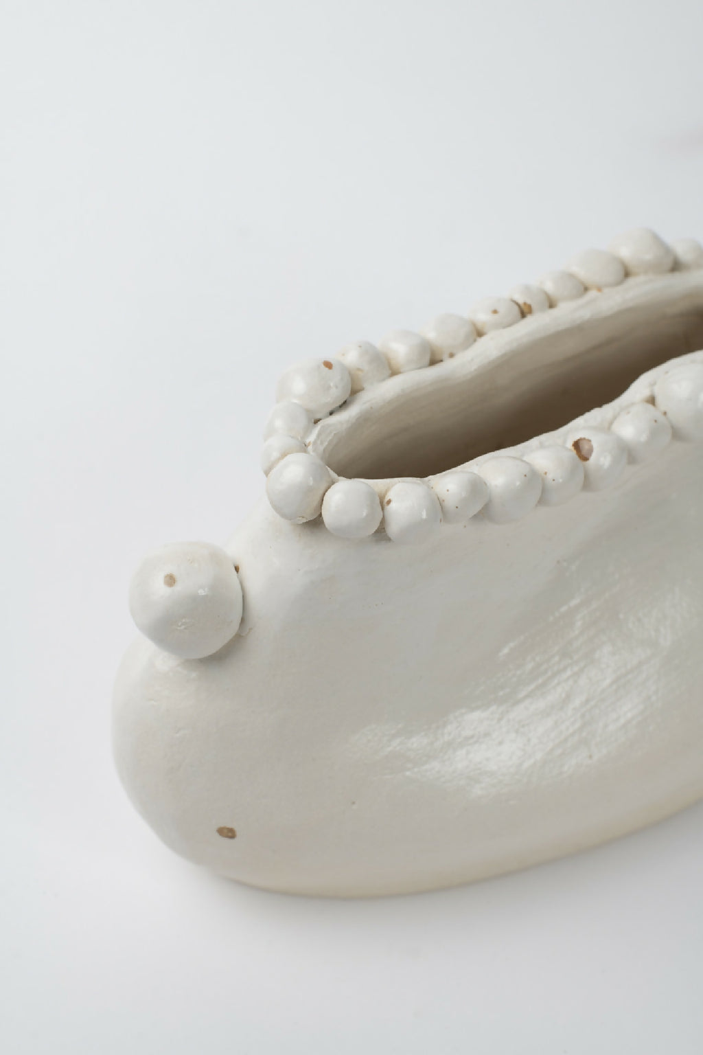 Gros plan du vase en céramique blanche: intérieur et bord perlé avec boule latérale