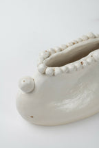 Gros plan du vase en céramique blanche: intérieur et bord perlé avec boule latérale