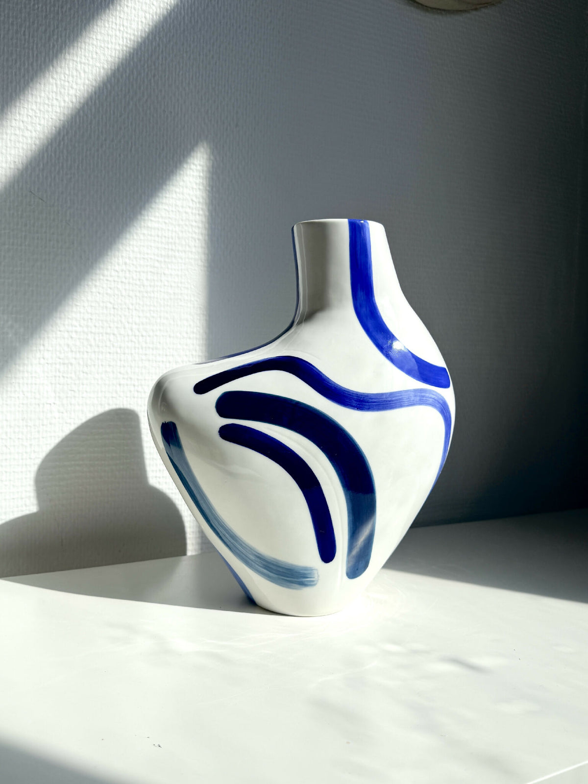Vase buste organique blanc avec motifs bleus, forme arrondie et col évasé