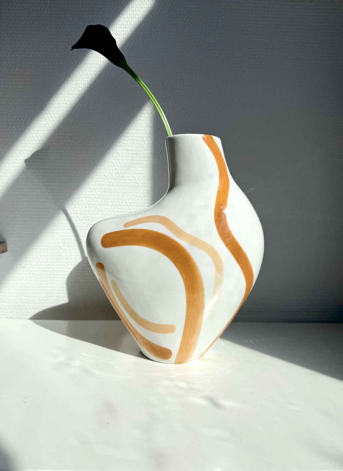 Vase buste organique blanc, décor orange en volutes, tige verte et fleur noire.