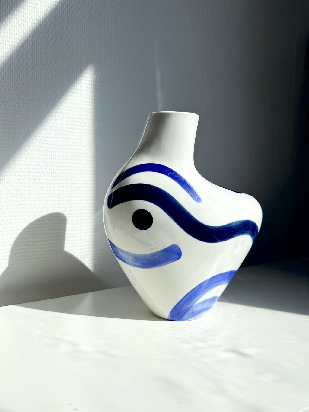 Vase buste organique blanc, décor bleu ondulé, silhouette arrondie et col court.