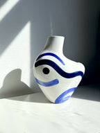 Vase buste organique blanc, décor bleu ondulé, silhouette arrondie et col court.