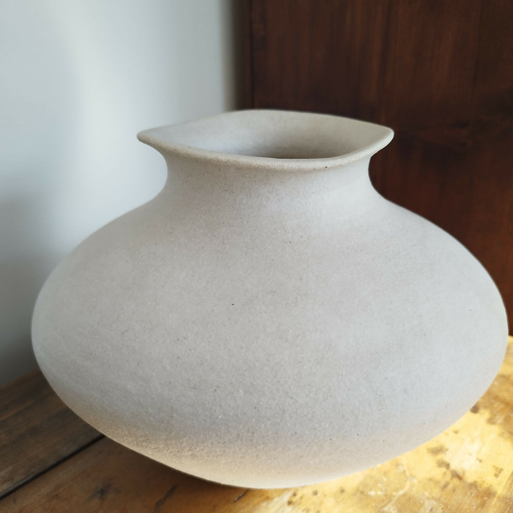 Vase en céramique blanc cassé, vue de face, col évasé et surface texturée