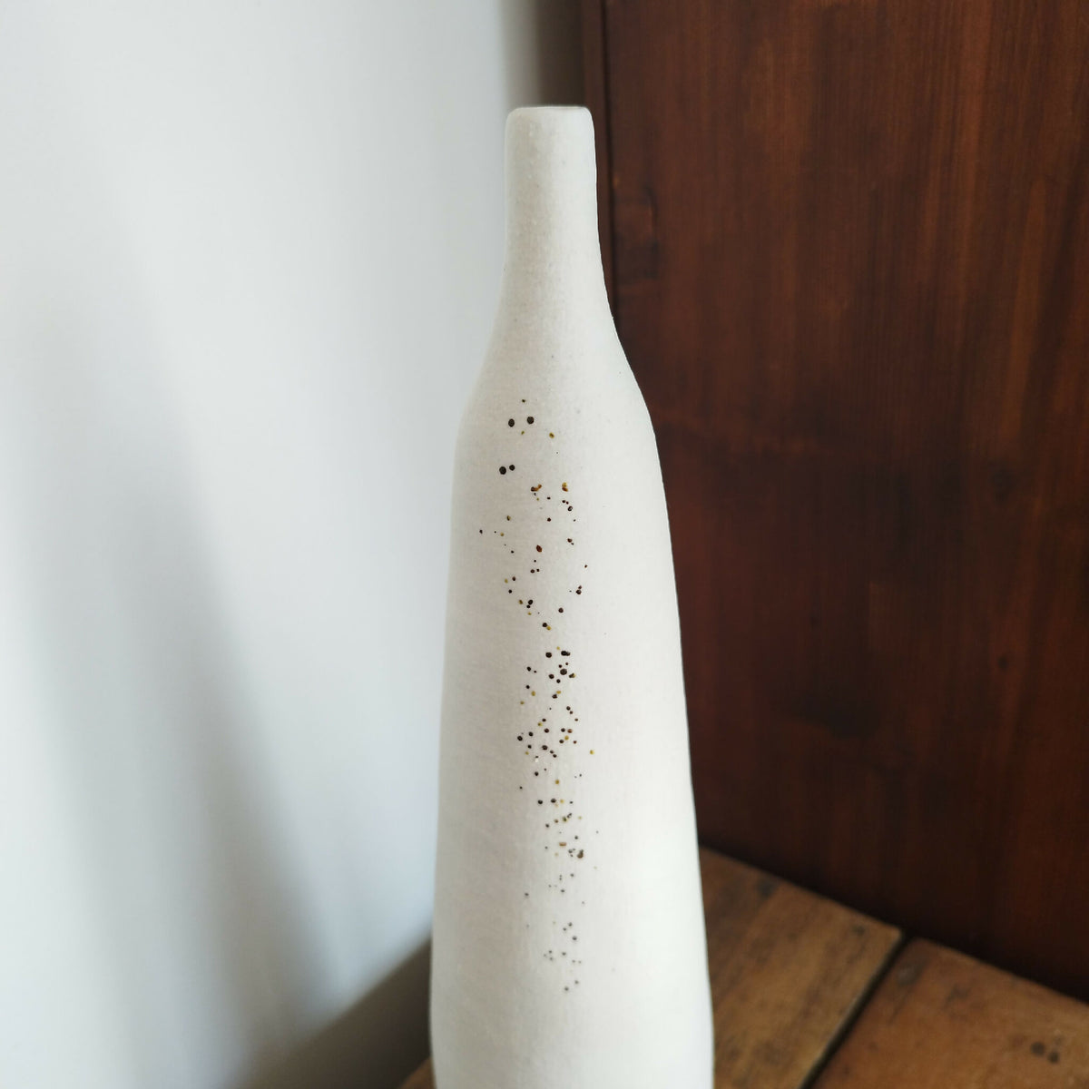Vase en céramique blanc, col étroit, décor de points brun-noir et doré.