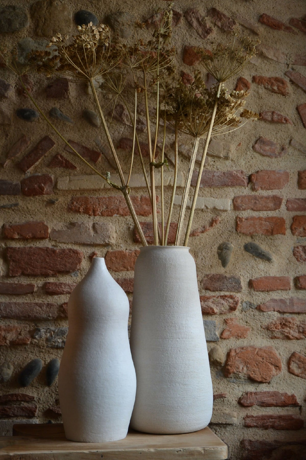 Deux vases en céramique blanc cassé avec tiges de fleurs sèches