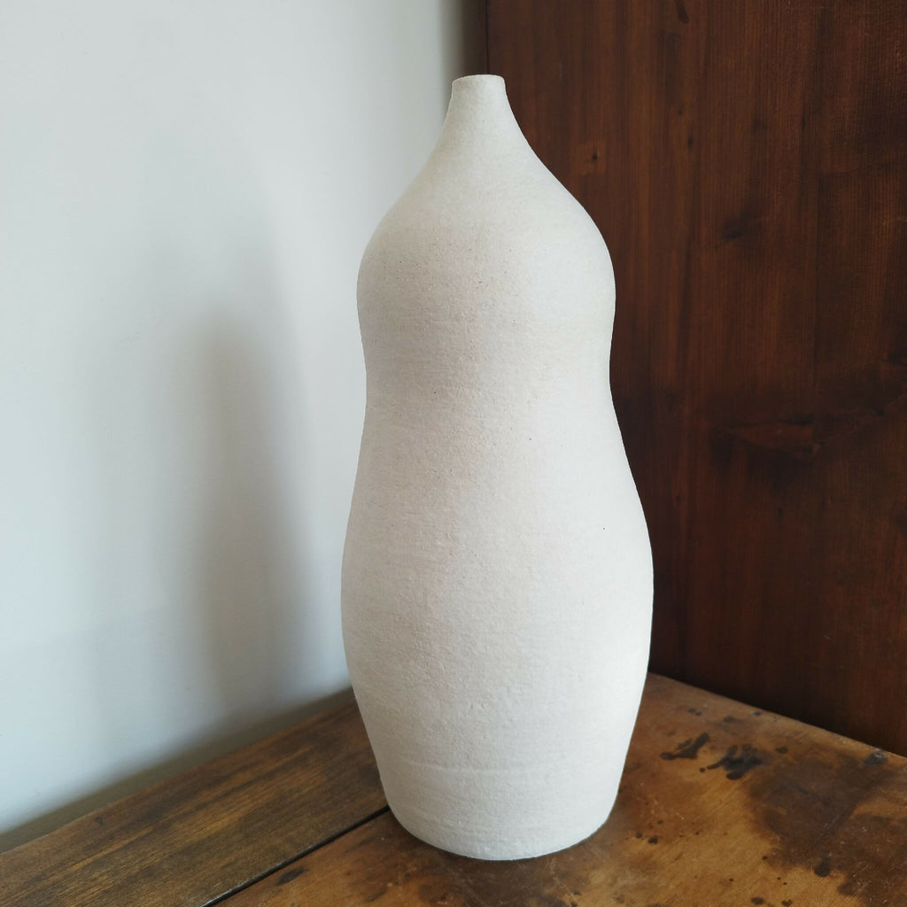 Vase en céramique blanc cassé, forme haute et étroite, surface grainée