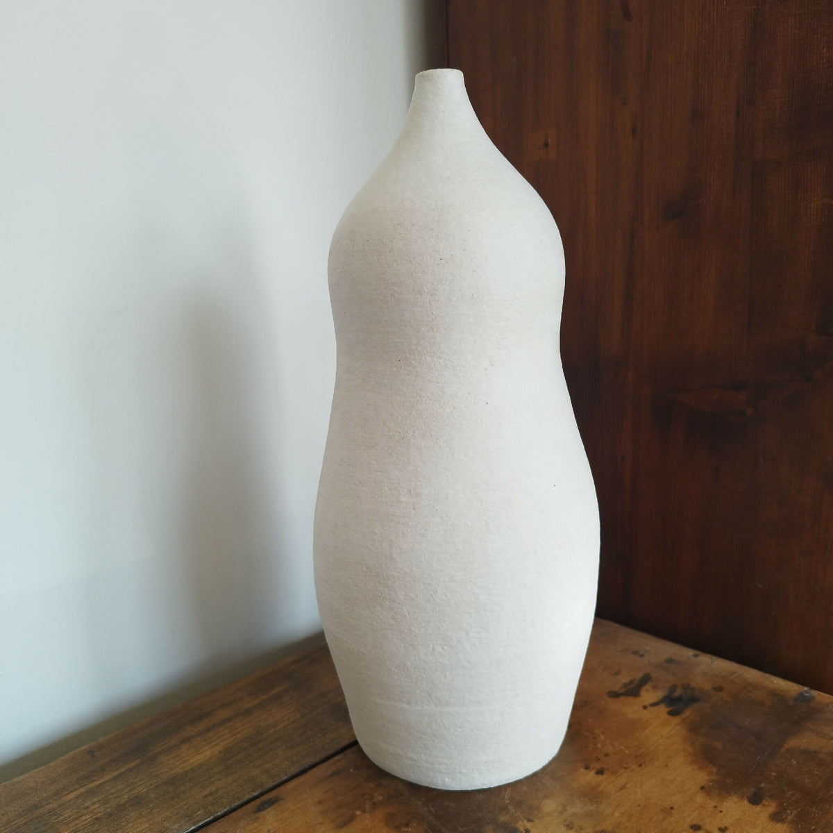 Vase en céramique blanc cassé, forme haute et étroite, surface grainée