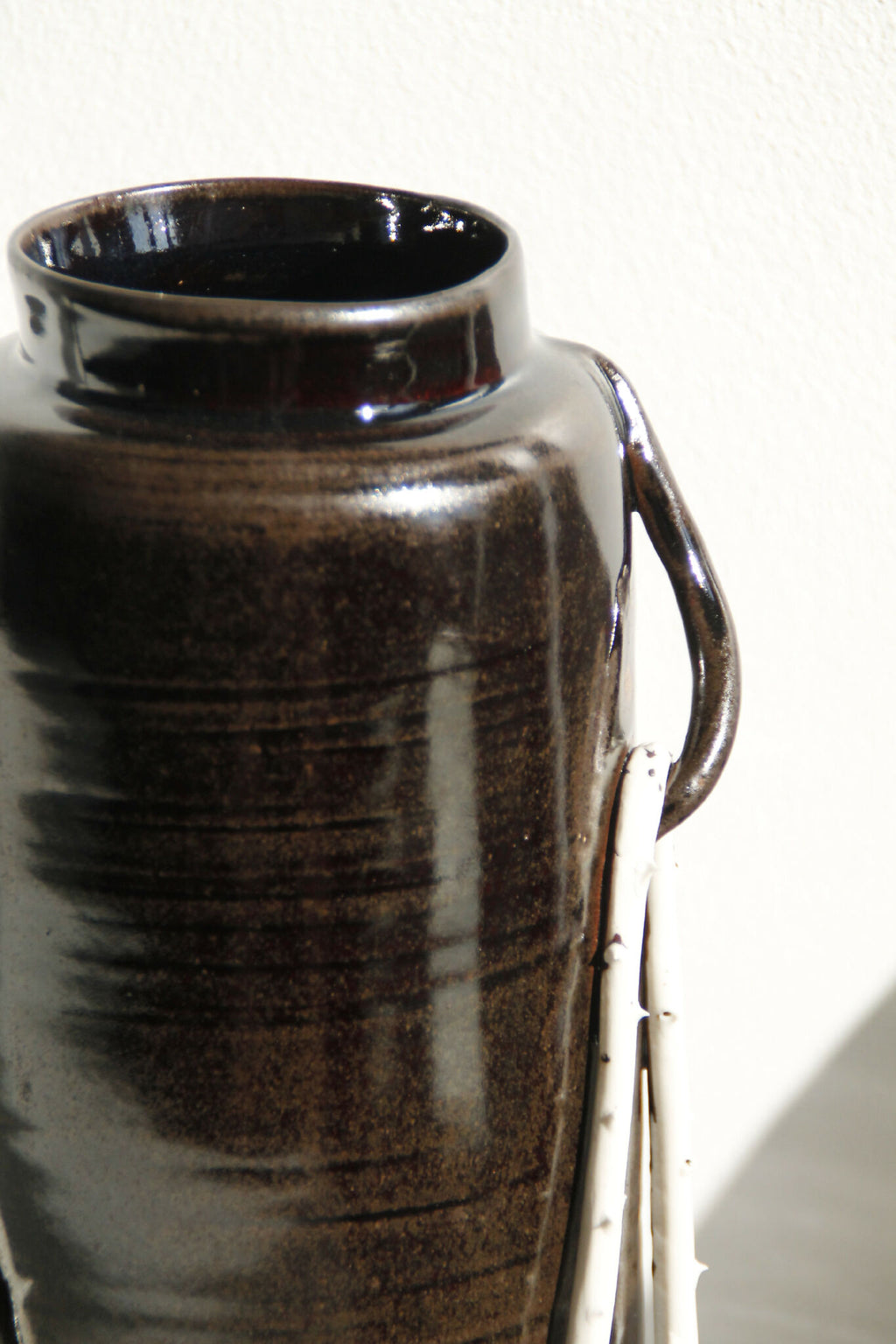 Goulot et bord d’un vase en céramique noir brillant, anse visible