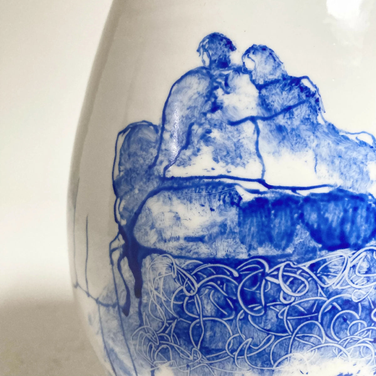 Vase blanc avec dessin bleu rapproché de couple assis et motifs décoratifs.