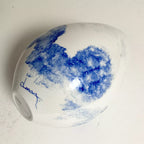Vase blanc bleu sur le côté, vue de la base avec étiquette circulaire.