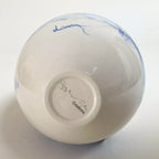 Vase goutte, dessous blanc avec texte « Creators » et signature bleue.