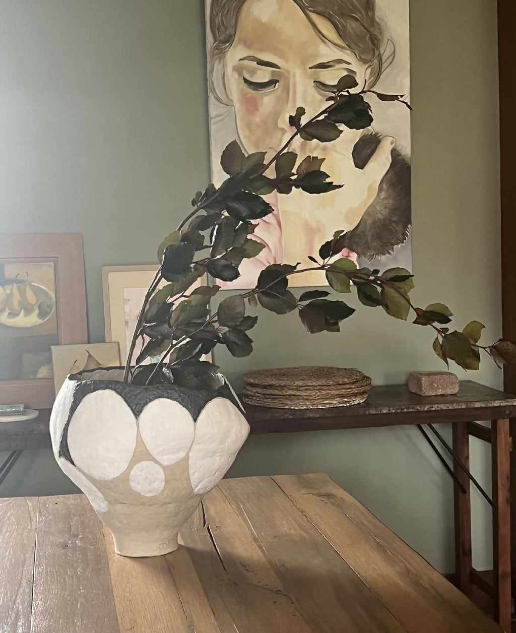 Grand vase beige à motifs galets blancs et bord noir, avec feuillage