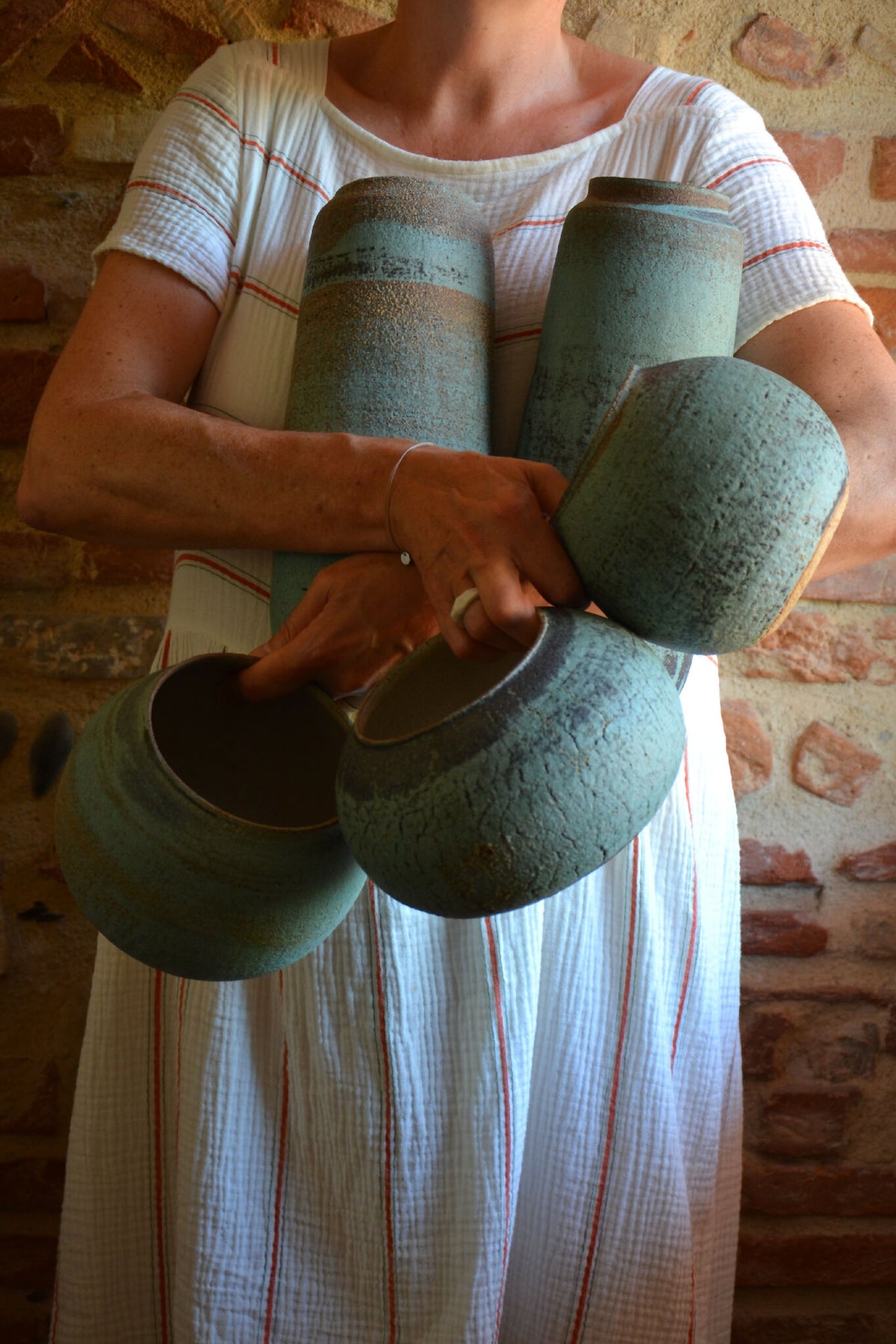 Vase en céramique bleu-vert tenu à la main, finition granuleuse