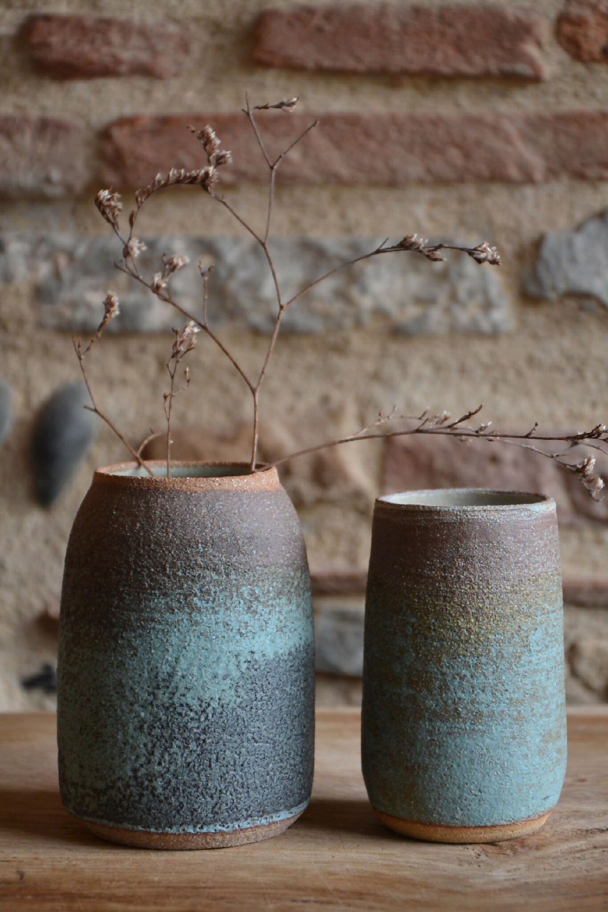 Vase en céramique RIVAGE deux hauteurs, texture bleu-vert mouchetée sur table
