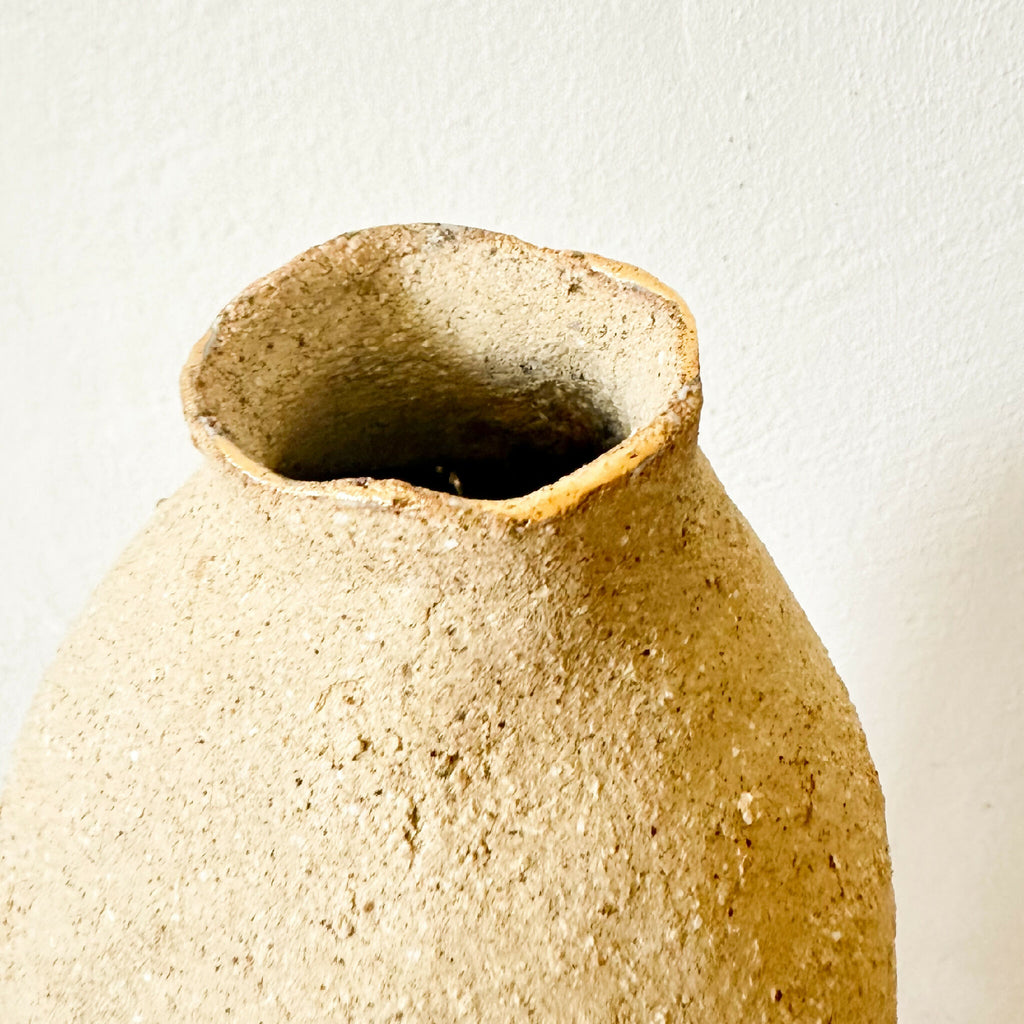 Vase en grès brut beige, gros plan de l’ouverture évasée et intérieur sombre.