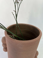 Vase en grès brun, vue intérieure avec tiges de fleurs vertes et bouquet.