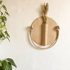 Vase mural en céramique beige en forme de soleil avec ouverture et anse, fixé au mur