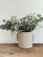 Vase en grès beige texturé, touches d’éclats, anses rondes, forme cylindrique.