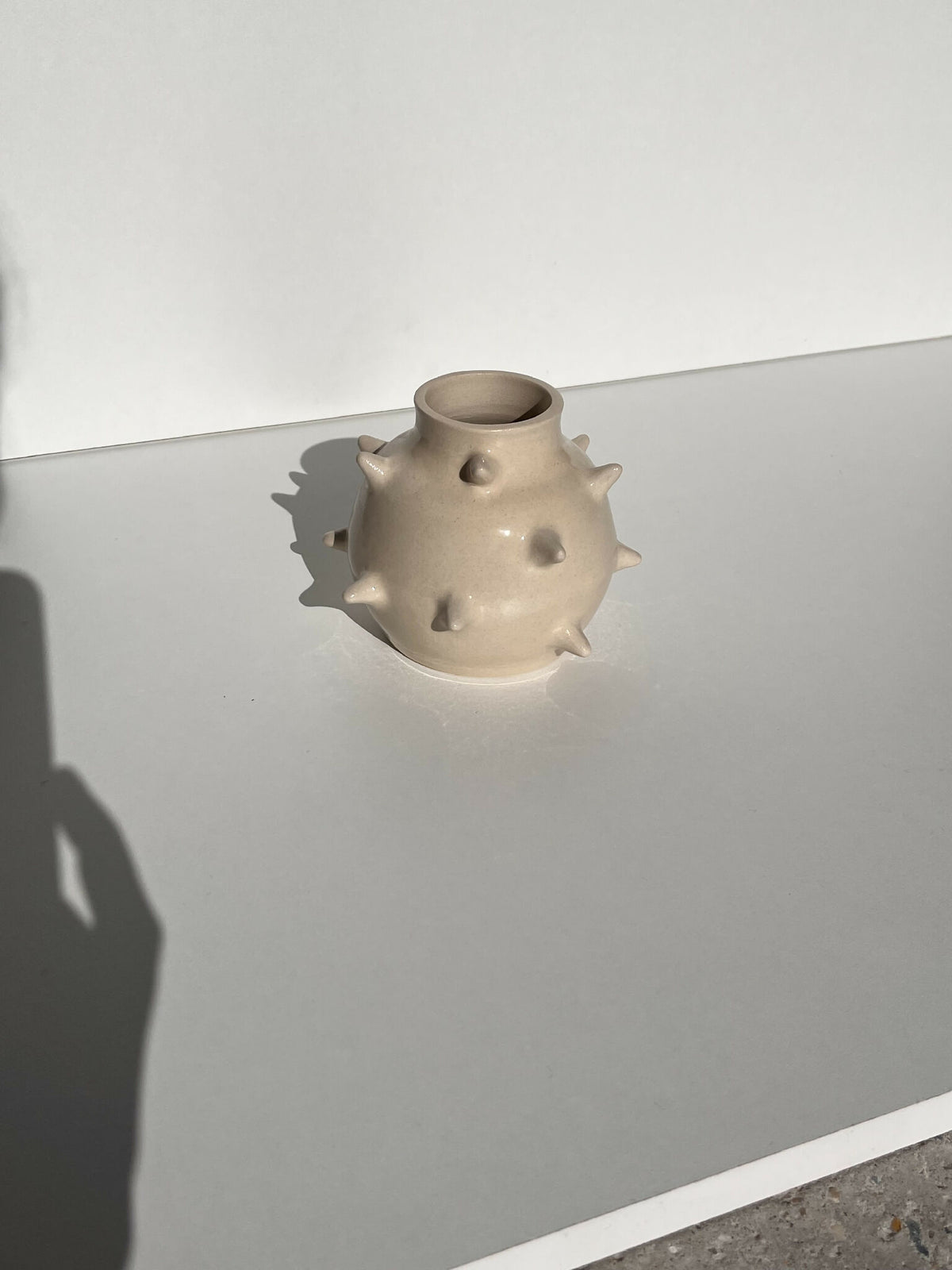 Petit vase en céramique beige à pointes, vue de côté, ouverture en cercle