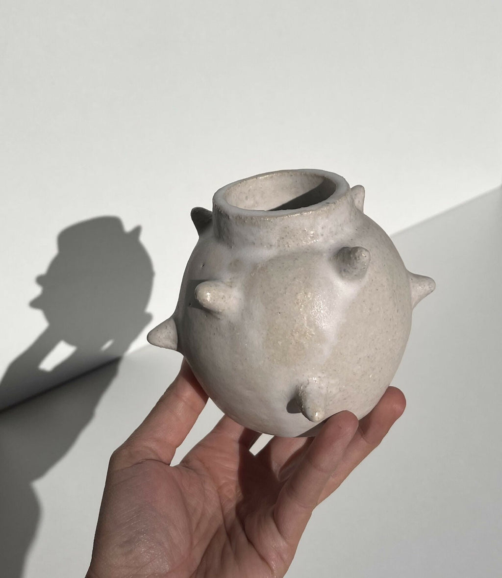 Vase en céramique gris argenté à reliefs, col évasé, tenue à la main