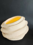 Vase sculpture blanc cassé avec ouverture et intérieur jaune, vue trois-quarts