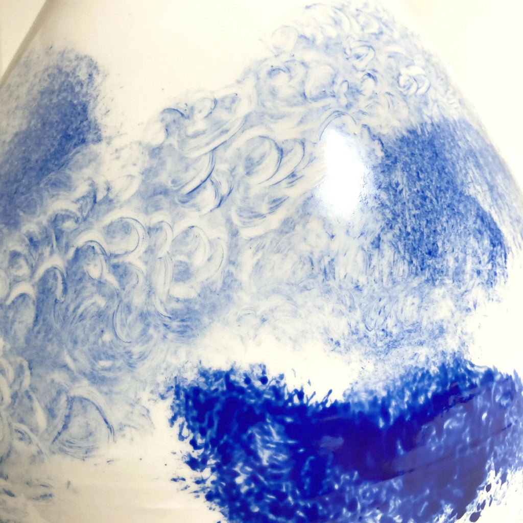 Vase en céramique blanc avec peinture bleu, motifs floraux en relief, gros plan.