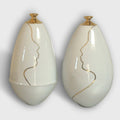 Vase soliflore en céramique blanche, col doré et contour de visage au trait.