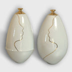 Vase soliflore en céramique blanche, col doré et contour de visage au trait.