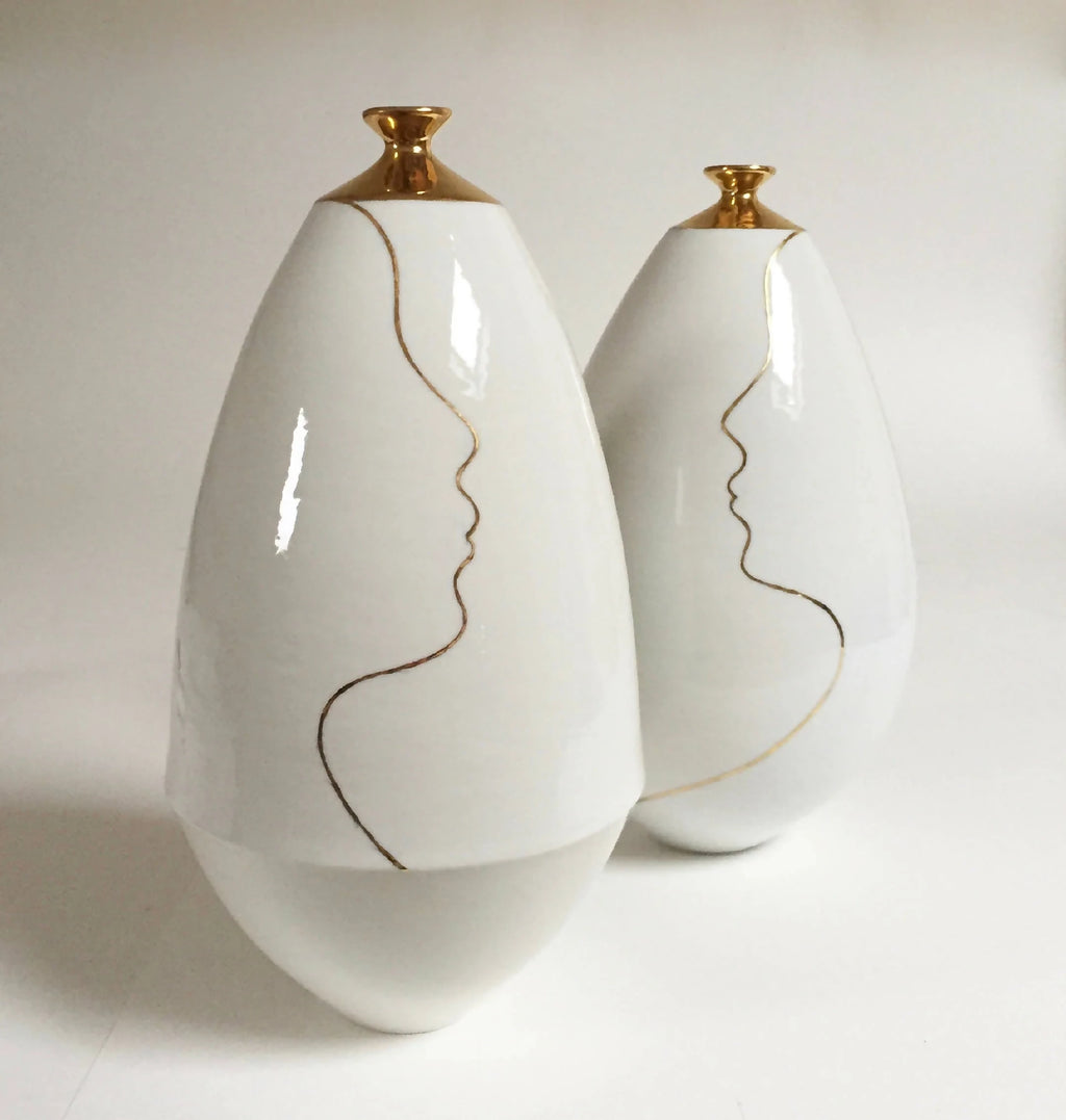 Vases soliflores blanc ivoire, cols dorés, lignes de visage au trait.