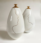 Vases soliflores blanc ivoire, cols dorés, lignes de visage au trait.