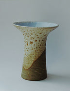 Vase tulipe en céramique beige et vert, bord intérieur bleu, surface tachetée.