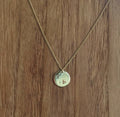 Collier à chaîne dorée et pendentif rond clair avec petit motif gravé