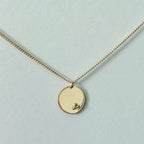 Collier doré à pendentif rond façon médaillon avec petit motif en relief