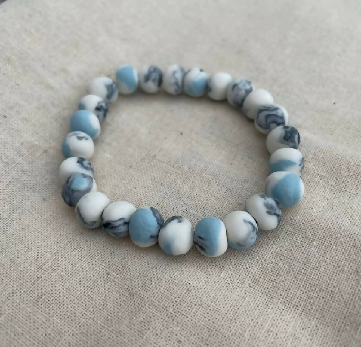 Bracelet femme en perles de porcelaine bleu clair et blanches, motif marbré.