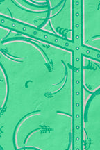 Détail de tissu vert émeraude, cadre à picots et arabesques sur fond uni
