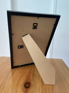 Cadre noir vu de dos, carton beige et attaches au dos, plaque en métal