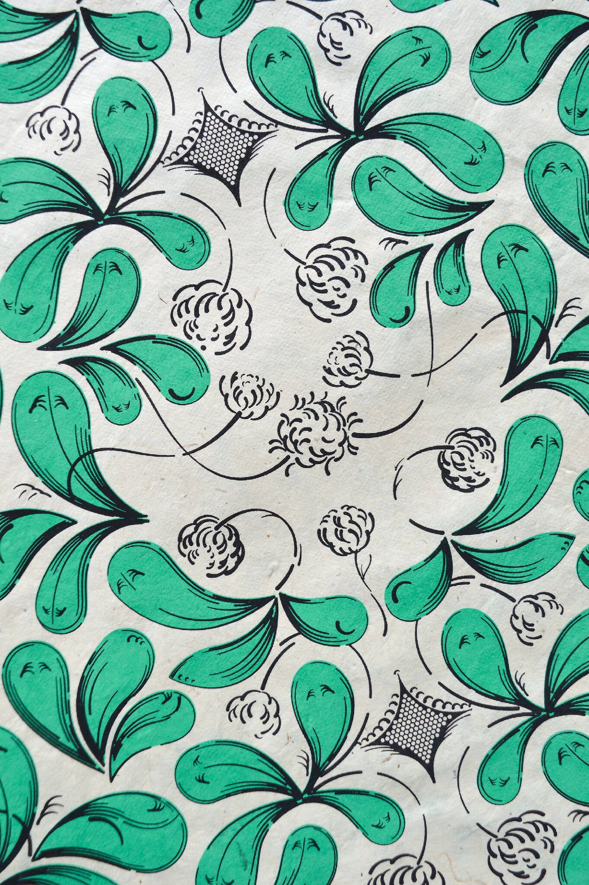 Coupon de tissu imprimé vert, feuilles et fleurs, contours noirs sur fond clair