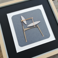 Chaise décorative en bois dans cadre blanc, fond gris-bleu, vue de face