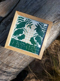 Cadre en bois avec illustration végétale verte et cage dorée sur fond crème.