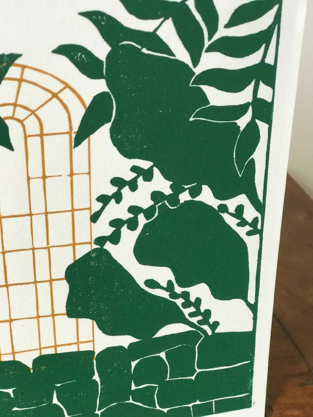 Détail de l’illustration: cage dorée et grandes feuilles vertes sur fond clair.