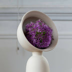 Vase soliflore en céramique blanc cassé, forme évasée, tige centrale, fleurs violettes