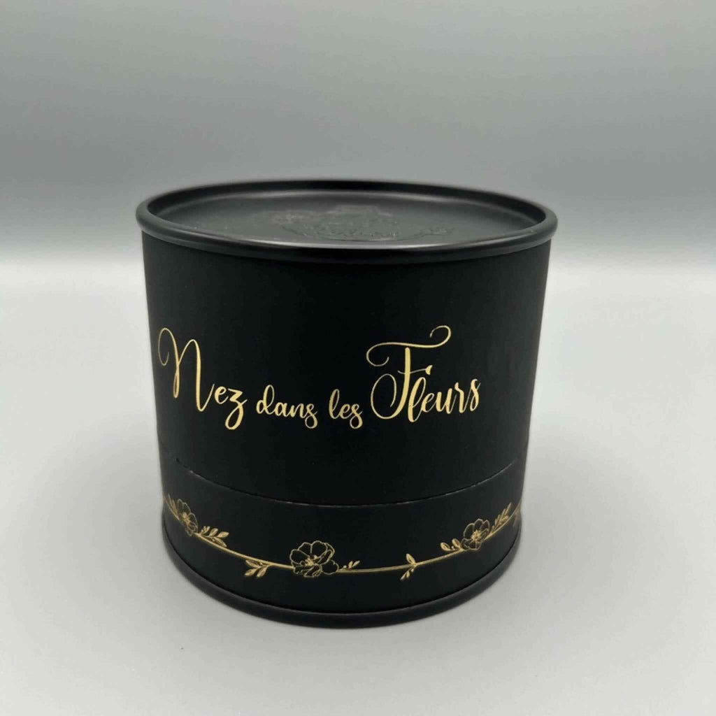 Boîte parfumée noire ronde avec couvercle et inscription dorée « Nez dans les Fleurs »