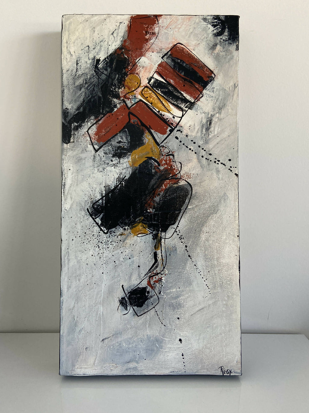 Tableau abstrait sur fond clair, composition rouge/noir avec touches jaunes et éclaboussures.
