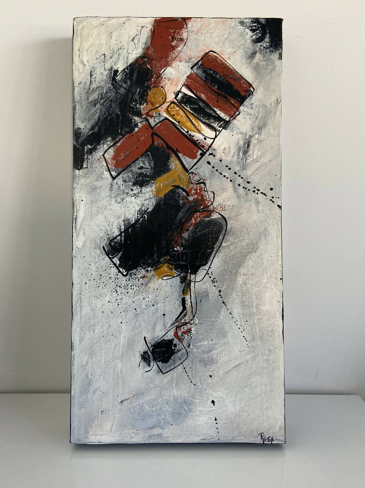 Tableau abstrait sur fond clair, composition rouge/noir avec touches jaunes et éclaboussures.